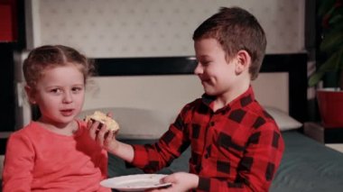 girl in pink skirt plays with guy in black and red plaid shirt, feeds her cake