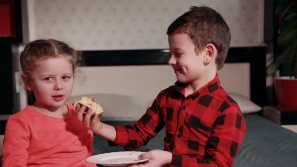 Girl in pink skirt plays with guy in black and red plaid shirt, feeds her cake — Αρχείο Βίντεο