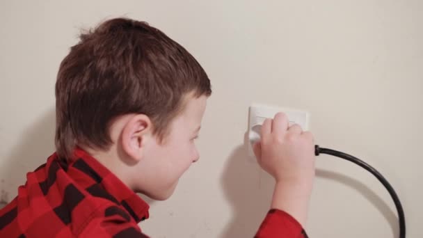 Cute guy rubs his hands, pushes an electric plug into socket — Stockvideo