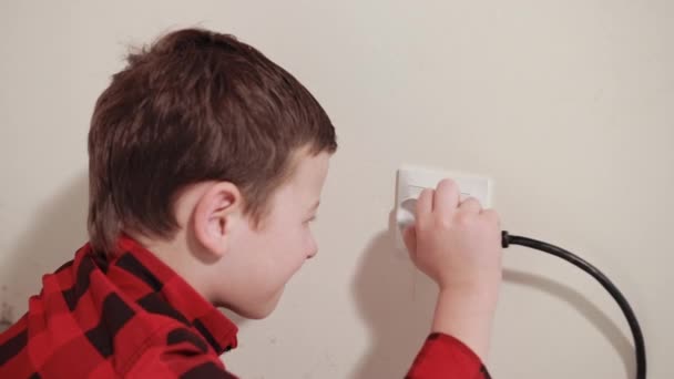 cute guy rubs his hands, pushes an electric plug into socket