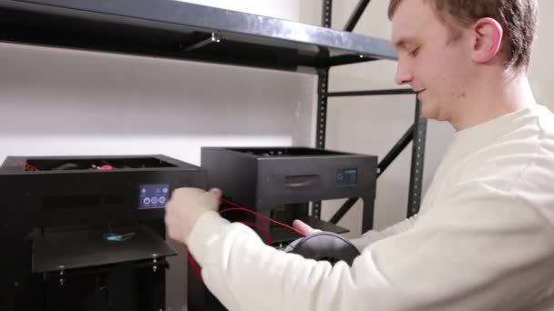 Young man unwinds and extracts a red plastic thread cable from the coil. — ストック動画