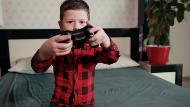 Lindo chico jugando videojuego, sosteniendo joystick, teniendo un tiempo emocional — Vídeos de Stock