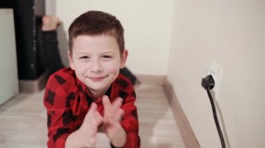 cute guy in red black plaid shirt rubs hands, pulls electric plug out of socket