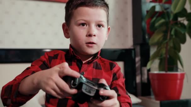 Lindo chico jugando videojuego, sosteniendo joystick, teniendo un tiempo emocional — Vídeo de stock