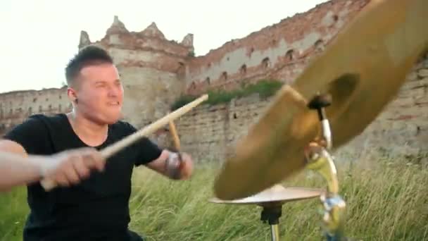 Drummer plays the drum set and cymbals on street, near the destroyed building — Stock Video