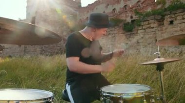 siyah şapka giymiş müzisyen davulcu, davul seti ve ziller, sokakta oynuyor