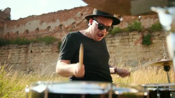 Μουσικός ντράμερ ντυμένος με μαύρο καπέλο, παίζοντας ντραμς και κυπαρίσλα, στο δρόμο — Αρχείο Βίντεο