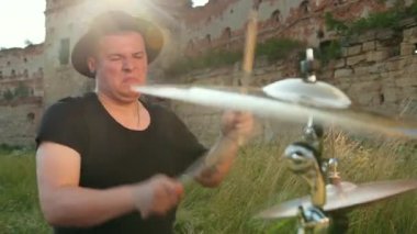 davulcu, davul seti ve ziller çalan, yıkılmış bir binanın yakınında sokakta