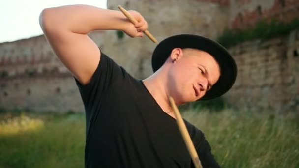 Professioneller Schlagzeuger, mit schwarzem Hut bekleidet, dreht Drumsticks auf der Straße — Stockvideo