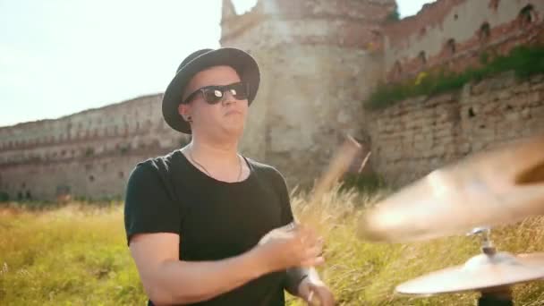 Musician drummer dressed in black hat, playing drum set and cymbals, on street — Stock Video