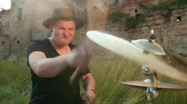 müzisyen davulcu siyah giysiler, şapka giymiş, davul seti ve ziller çalma