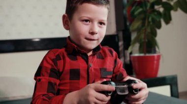 Sevimli çocuk video oyunu oynuyor, elinde joystick tutuyor, duygusal zaman geçiriyor.