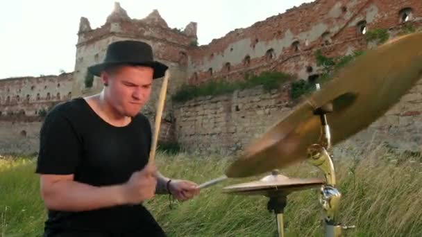 Барабанщик, граючи на барабанах і цимбалах, на вулиці біля зруйнованої будівлі — стокове відео