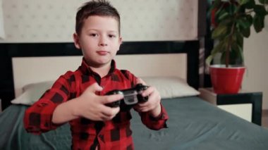 Sevimli çocuk video oyunu oynuyor, elinde joystick tutuyor, duygusal zaman geçiriyor.