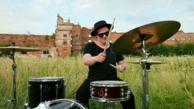 müzisyen davulcu siyah giysiler, şapka giymiş, davul seti ve ziller çalma