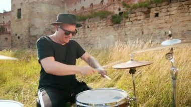 davulcu, davul seti ve ziller çalan, yıkılmış bir binanın yakınında sokakta