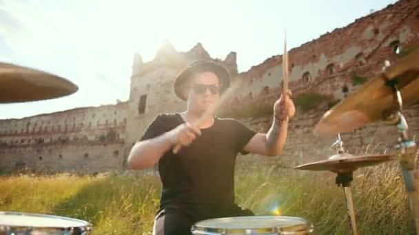 Drummer, playing drum set and cymbals, on street near a destroyed building — Stock Video