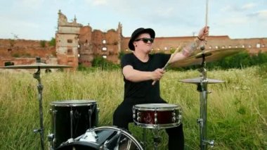 davulcu, davul seti ve ziller çalan, yıkılmış bir binanın yakınında sokakta