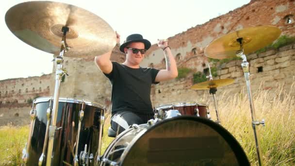 Muzician toboșar îmbrăcat în pălărie neagră, cântând set de tambur și cymbals, pe stradă — Videoclip de stoc