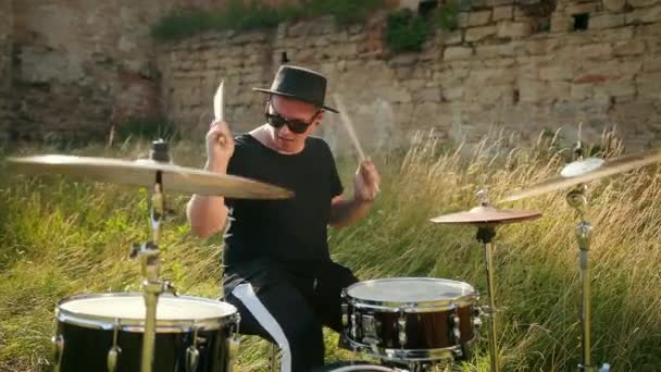 Bubeník, hrající na bicí souprava a činely, na ulici nedaleko zničené budovy — Stock video