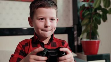 Sevimli çocuk video oyunu oynuyor, elinde joystick tutuyor, duygusal zaman geçiriyor.