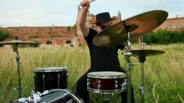 siyah şapka giymiş müzisyen davulcu, davul seti ve ziller, sokakta oynuyor