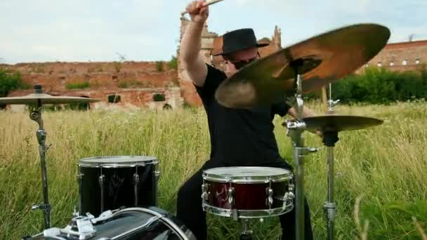 Musician drummer dressed in black hat, playing drum set and cymbals, on street — Stock Video