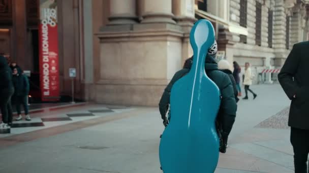 Homem caminha pela rua e carrega caixa azul de volta com instrumento musical — Vídeo de Stock