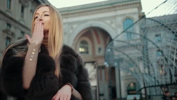 Junge blonde Frau flirtet in der City Street. Küsse blasen, winken, lächeln, — Stockvideo
