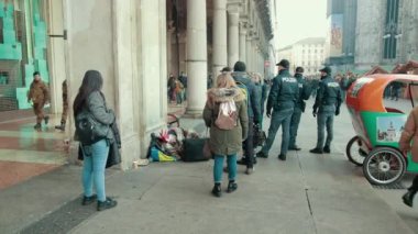 Noel Baba şapkalı evsiz adam kaldırımda yatıyor, etrafı sarılmış polis memurları.