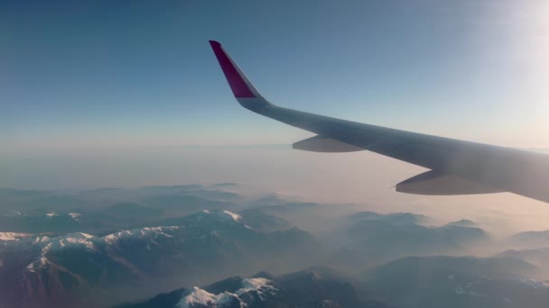 Ala de un avión que vuela sobre una hermosa vista de los Alpes suizos . — Vídeo de stock