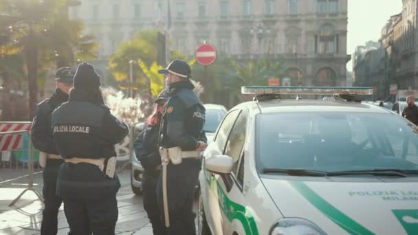 Czterech policjantów stoi w pobliżu kompanii patrolującej ulicę. — Wideo stockowe