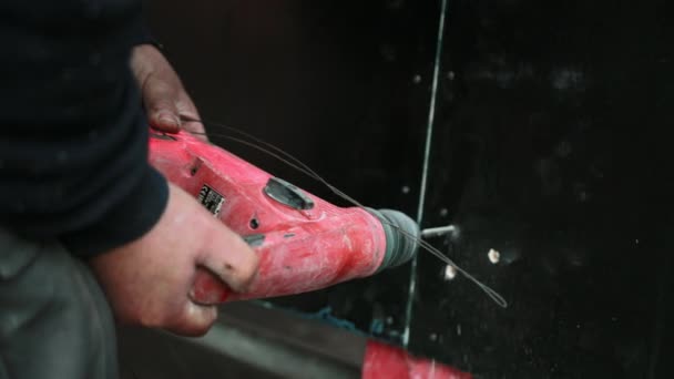 Primer plano de un taladro rojo que taladra agujero en la pared . — Vídeos de Stock