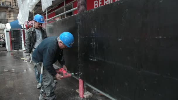 穿着蓝色防护面罩的男性建筑工人在工作。钻一个孔 — 图库视频影像