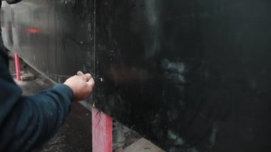Mans 'ın biri metal telleri çitin içindeki delikten geçirip bağlıyor. Kapat.