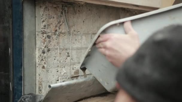 Une main de Mans avec la spatule mélange la solution liquide dans la brouette pour la construction — Video