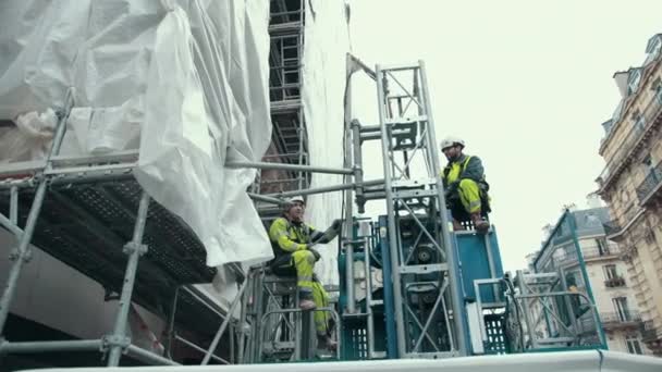Férfi építőmunkások világos zöld egyenruhában, öltöny megy fel működő lift — Stock videók