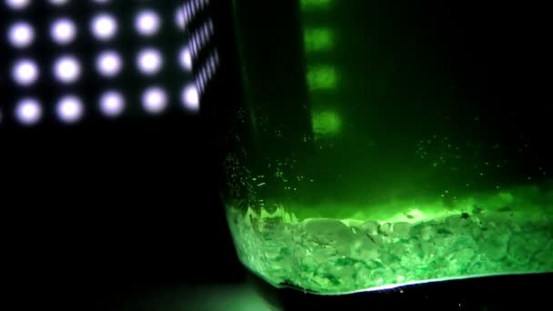 Vidro com líquido verde em um fundo de luzes — Vídeo de Stock