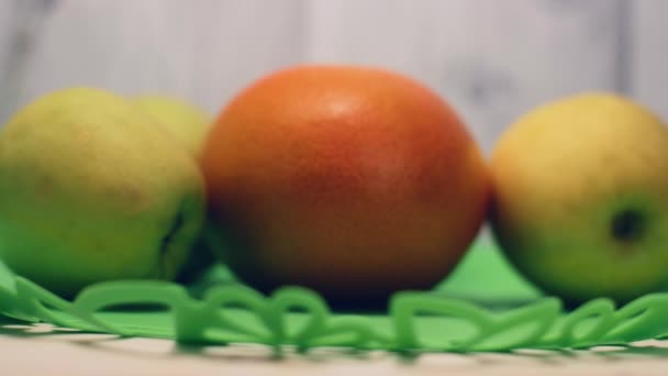 Bodegón. Una mano de hombre pone una manzana verde en el plato con frutas . — Vídeo de stock