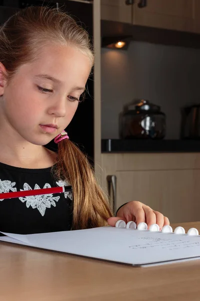 Mladá dívka dělat domácí úkoly v kuchyni u stolu — Stock fotografie
