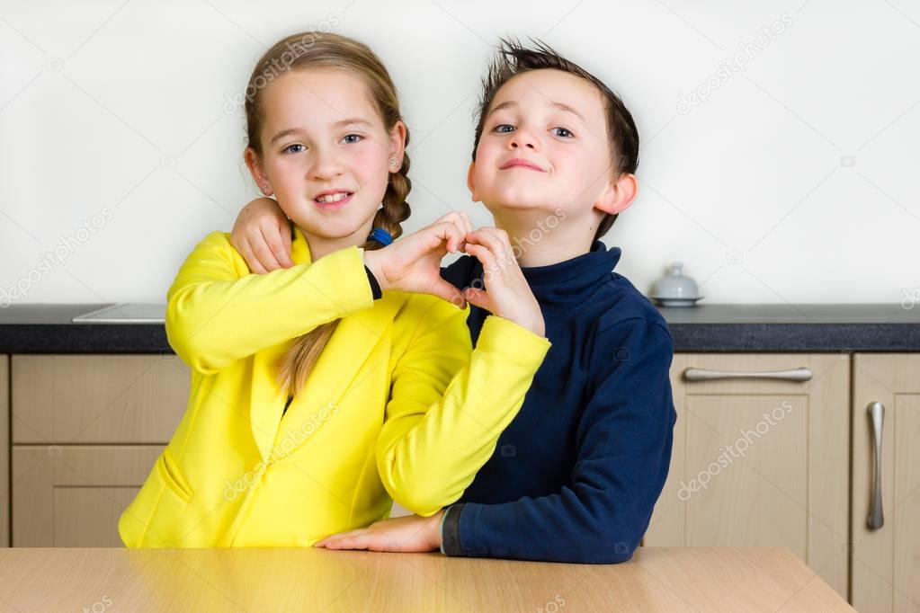 Siblings hug forming a heart with hand