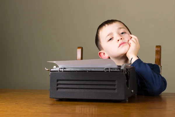 Malý chlapec myslel před Starý psací stroj — Stock fotografie