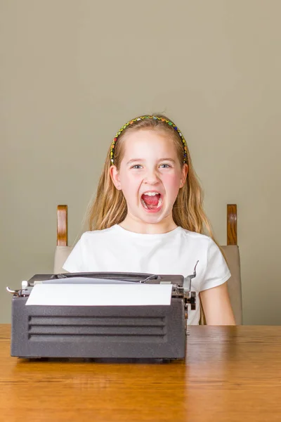 Mladá dívka zlobí při práci na Starý psací stroj — Stock fotografie