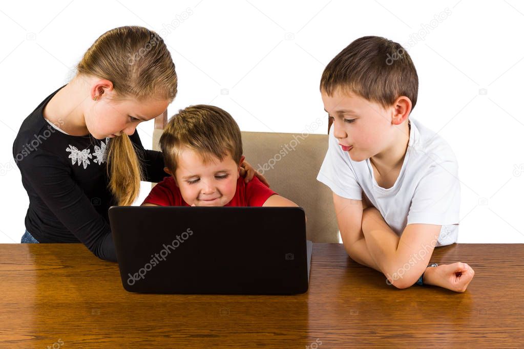 cute little boy playing on a laptop getting help from his older sister and brother