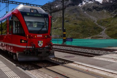 Red RhB train in Ospizio Bernina railway station, Grisons, Switzerland. clipart