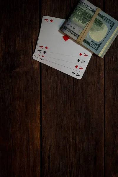 Image of a bundle of money on top of playing cards on a wooden t — Stock Photo, Image