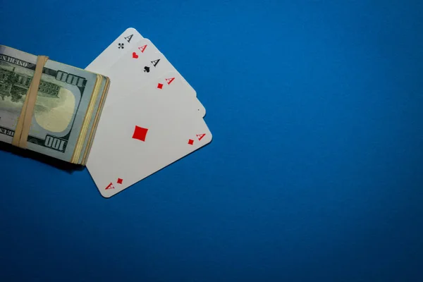Image of a bundle of money on top of playing cards on a blue bac — 图库照片
