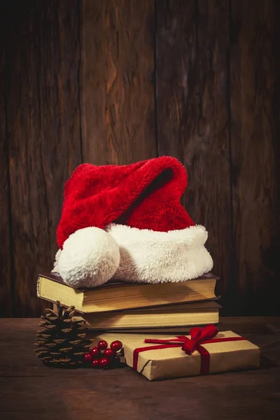 Weihnachtsmann-Hut auf Büchern, Packschachtel mit Geschenk, saftige Stimmung — Stockfoto