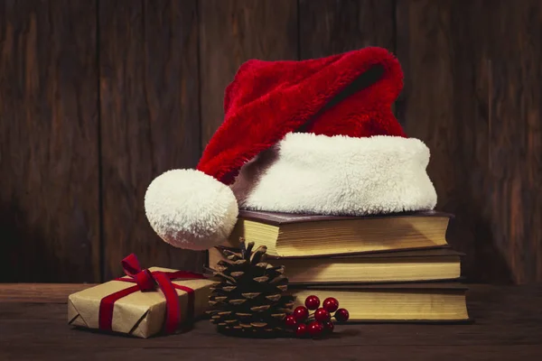 Sombrero de Papá Noel, libros, caja de embalaje con regalo, un viburnum jugoso a — Foto de Stock