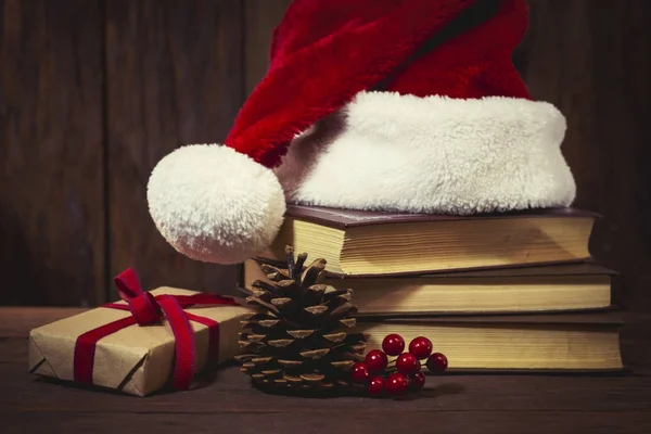 Un sombrero de Santa Claus, libros, una caja de embalaje, un viburnum y una estafa — Foto de Stock